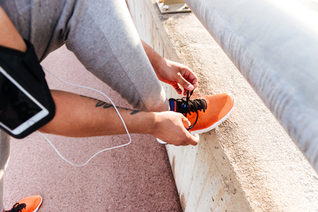 Cropped image of young sportsman standing outdoors tie his laces.の写真素材