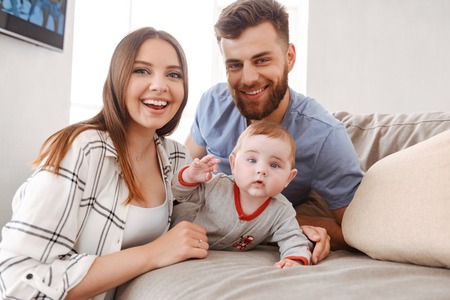 Image of happy young family. Parents having fun with their little child indoors at home.の写真素材