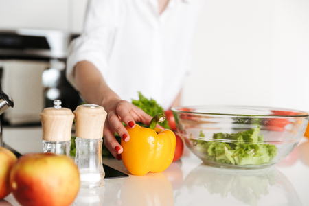 Cropped image of young woman in kitchen indoors at home cooking.の写真素材