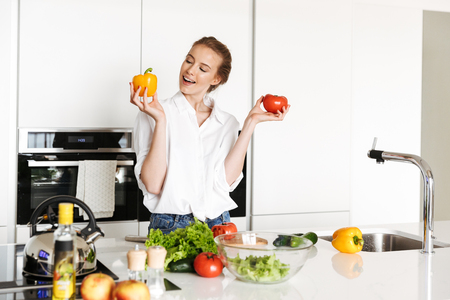Image of young amazing woman standing in kitchen indoors at home cooking.の写真素材