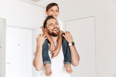 Photo of happy young man father dad having fun with his son indoors at home.の写真素材