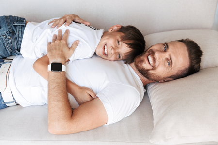 Image of handsome bearded man indoors at home with his son child having fun.の写真素材