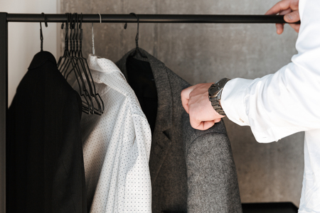 Close up of man picking jacket from a closetの写真素材
