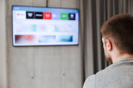 Back view of a man watching smart tv at home