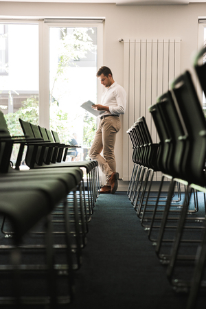 Portrait of a confident handsome formal dressed man standing with a tablet at the conference roomの写真素材