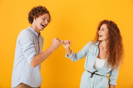 Photo of happy people man and woman smiling and hook each other's little fingers in conciliation or...