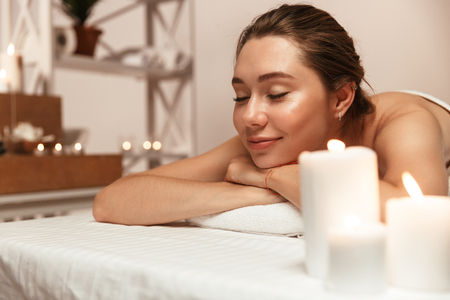 Image of amazing young beautiful woman lies in massage room in spa over candles.の写真素材