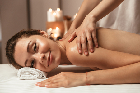 Delighted young woman having massage in the spa salonの写真素材