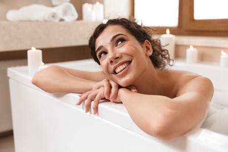 Image of young cute pretty woman in bathroom lies resting in bath.