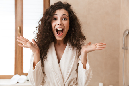 Image of excited beautiful surprised young cute woman looking camera in bathroom.の写真素材