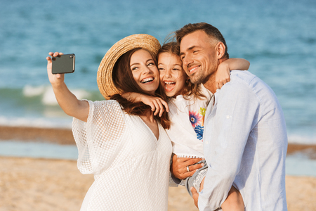 Happy family spending good time at the beach together, taking selfieの写真素材
