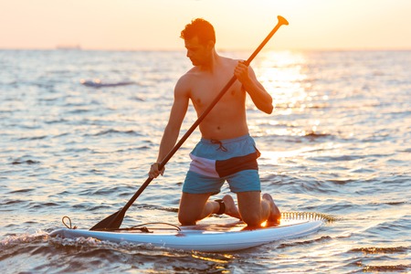Image of young handsome man kayaking on lake sea.の写真素材