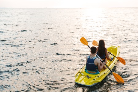 Back view of an attractive young couple kayaking on lake togetherの写真素材