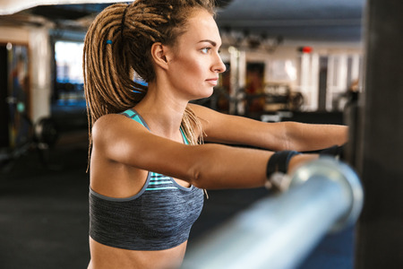 Portrait of beautiful fitness woman wearing tracksuit resting after doing sports in gym