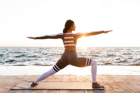 Image of amazing strong young fitness woman outdoors in the beach make yoga stretching exercises.の写真素材