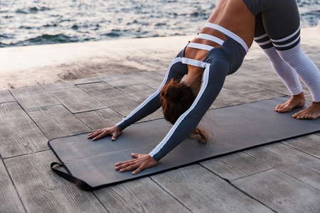 Image of amazing strong young fitness woman outdoors in the beach make yoga stretching exercises.の写真素材