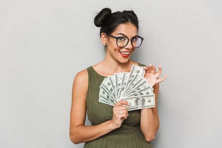 Portrait of a cheerful young woman isolated, showing money banknotesの写真素材
