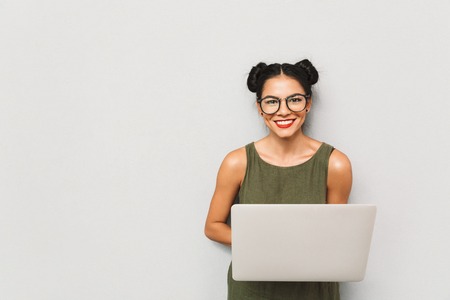 Portrait of a positive young woman isolated, using laptop computerの写真素材