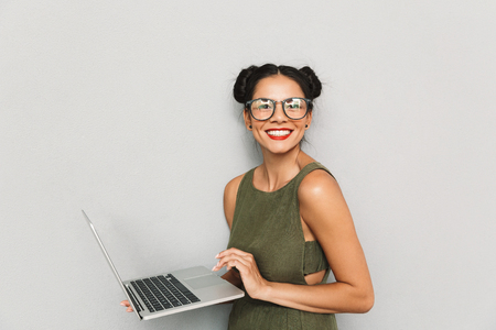 Portrait of a happy young woman isolated, using laptop computerの写真素材