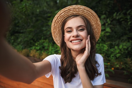 Happy young girl taking a selfie with outsretched hand at the park outdoors