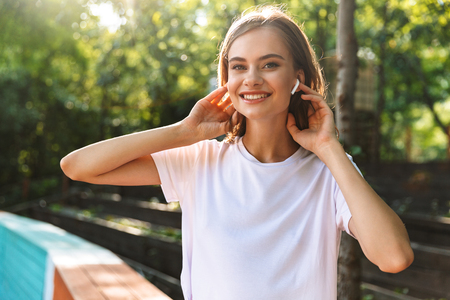 Smiling young girl listening to music with earphones at the park outdoorsの写真素材