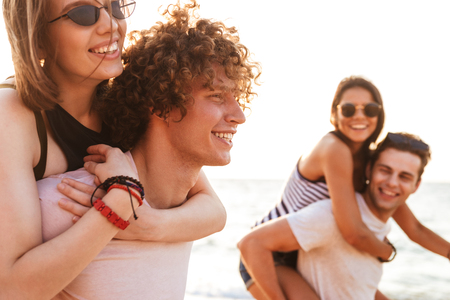 Picture of happy group of friends loving couples walking outdoors on the beach having fun.の写真素材