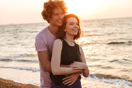 Image of cute young happy loving couple hugging outdoors on the beach.の写真素材