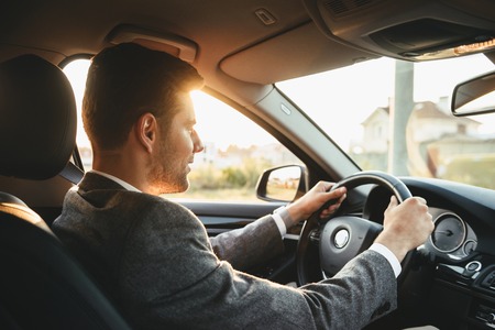 Smiling bussinesman in suit driving his carの写真素材
