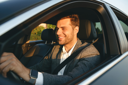 Confient smiling bussinesman in suit driving his carの写真素材