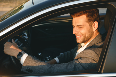 Happy bussinesman in suit driving his carの写真素材