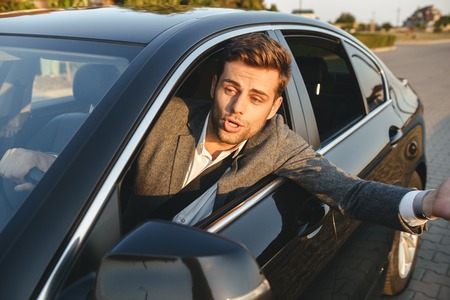 Close-up of an angry man looking outside car window, yellingの写真素材
