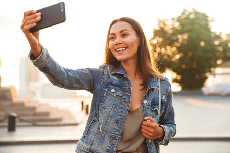 Image of young beautiful woman student walking in the park make selfie by mobile phone.の写真素材