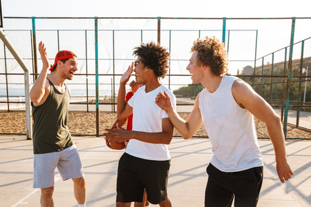Portrait of multiethnic sporty men playing basketball at the playground outdoor during summer sunny dayの写真素材