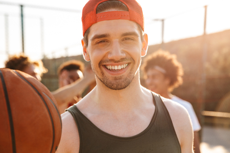 Close up of smiling man playing basketball with his team at the sport groundの写真素材