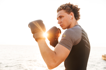 Photo of young handsome sports man boxer outdoors on the beach boxing in gloves.の写真素材