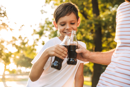 Close up of father spending time with his little son at the park, drinking fizzy drinksの写真素材