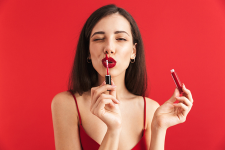 Photo of young beautiful woman posing isolated holding lip gloss doing makeup.の写真素材