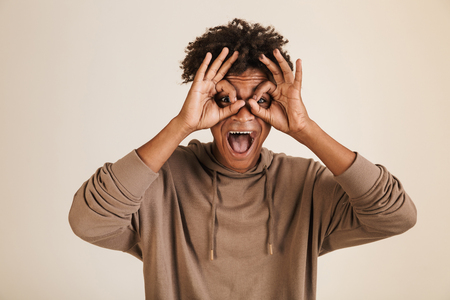 Portrait of a joyful young afro american man dressed in hoodie showing ok isolatedの写真素材