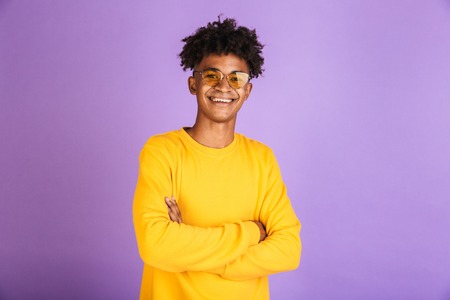 Portrait of a happy young afro american man in sweatshirt isolated, standing with arms foldedの写真素材