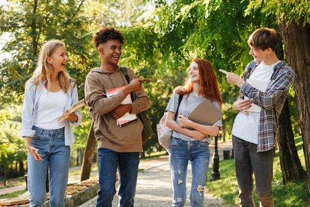 Group of laughing students walking at the campus outdoors, pointing fingersの写真素材
