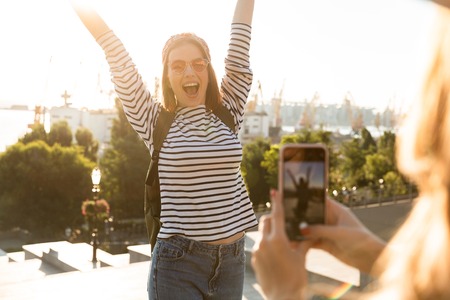 Excited young girl posing infront of camera to take a picture at the city streetの写真素材