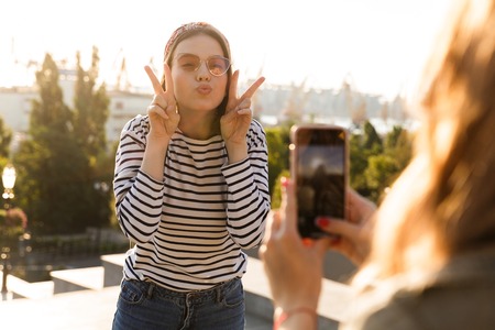 Funny young girl posing infront of camera to take a picture at the city streetの写真素材