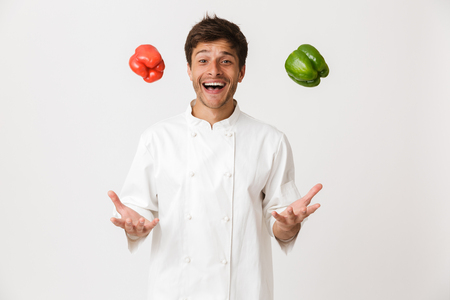 Image of emotional young chef isolated over white background holding paprika.の写真素材