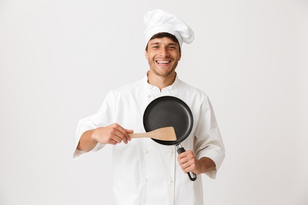 Image of handsome young chef man standing isolated over white wall background holding crockery.の写真素材