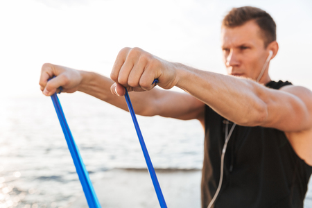 Picture of strong young sportsman outdoors at the beach make sport exercises with equipment.の写真素材