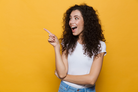 Photo of beautiful excited young cute woman posing isolated over yellow background pointing.の写真素材