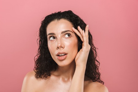 Portrait of amazing beautiful young woman with healthy skin posing isolated over pink background looking aside.の写真素材