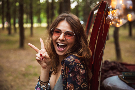 Image of attractive woman 20s wearing stylish accessories smiling while resting in forest campの写真素材
