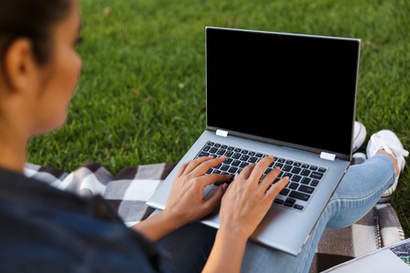 Cropped image of amazing beautiful young woman student in the park using laptop computer.の写真素材