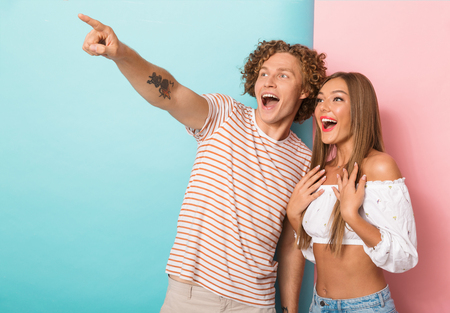 Portrait of a happy young couple standing pointing awayの写真素材